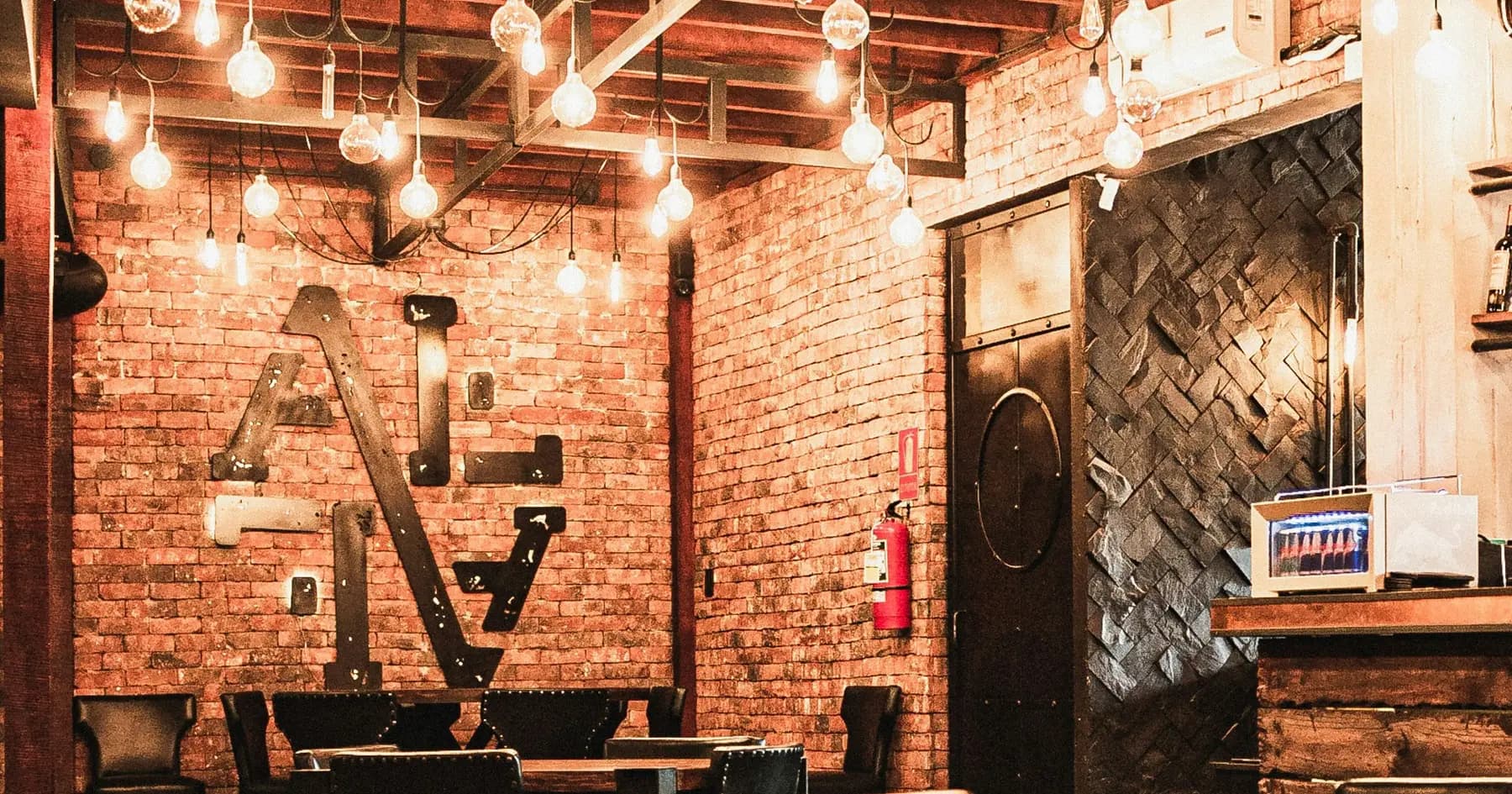 The dining room: brick walls, hanging bulbs and wooden tables