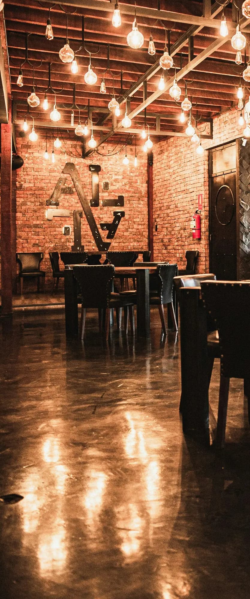 The dining room: brick walls, hanging bulbs and wooden tables