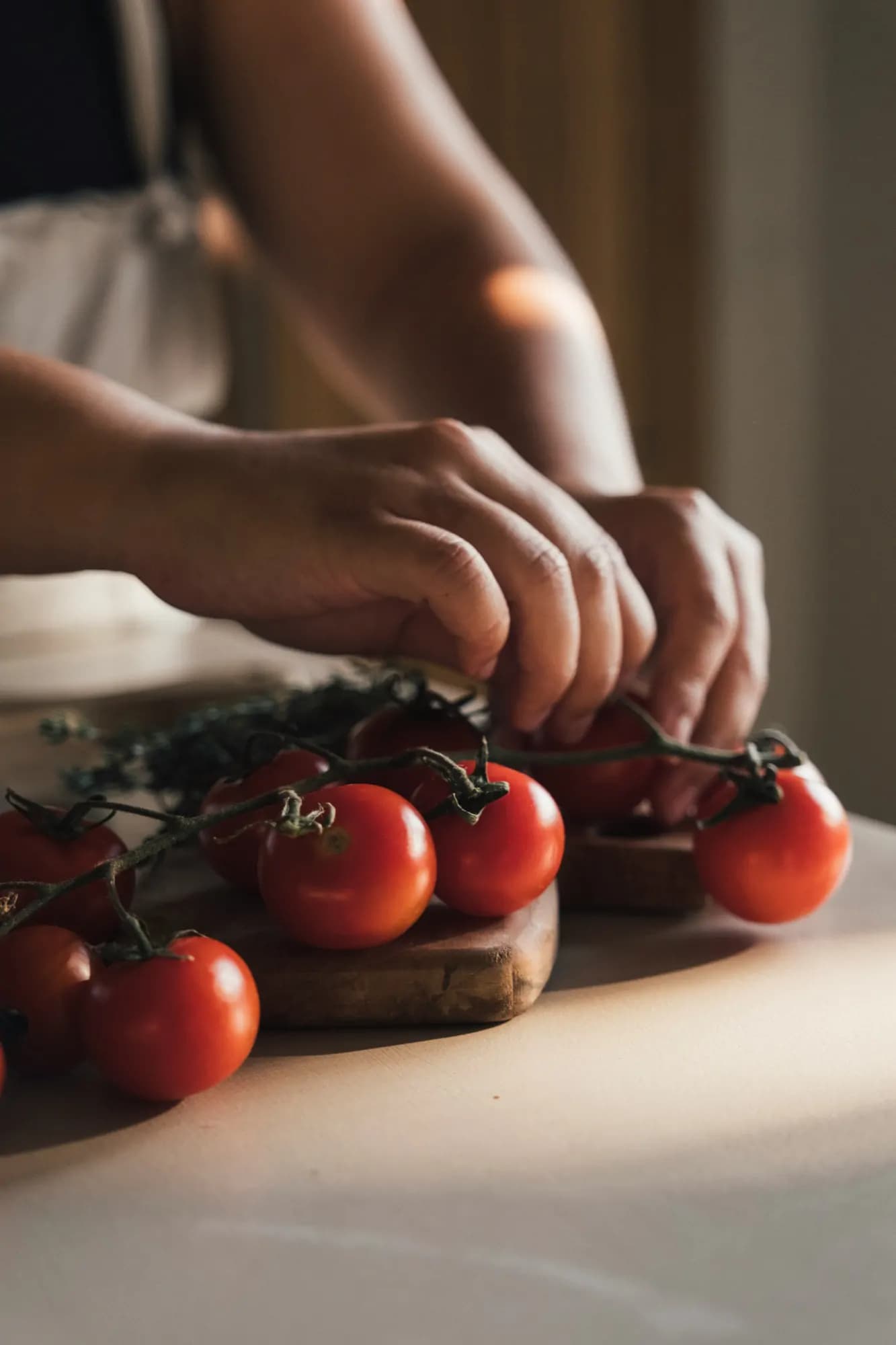 Hands placing vine tomatoes on a cutting board