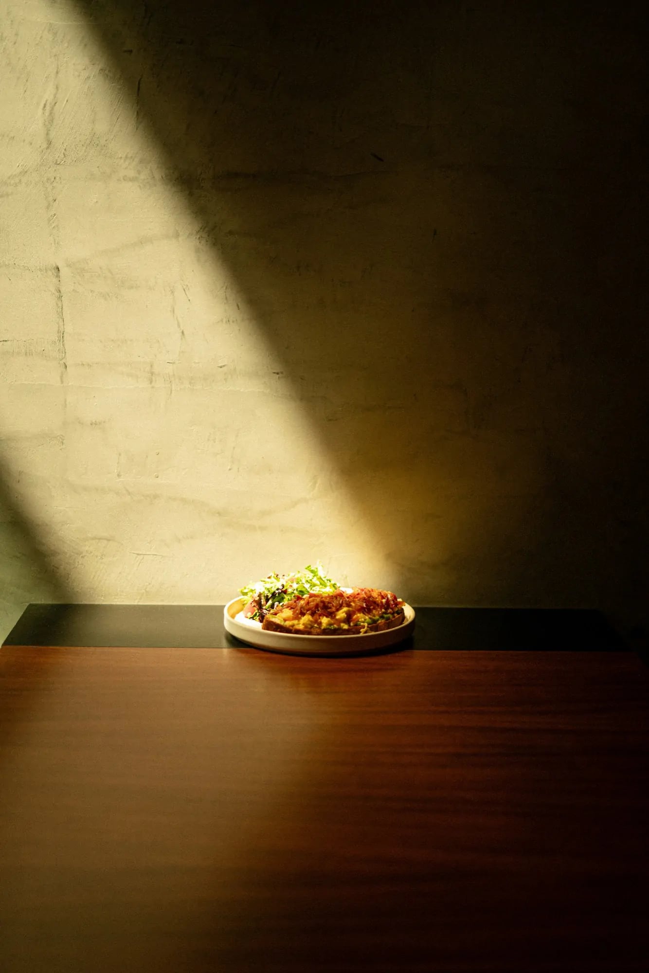 A single plate in a beam of afternoon light on a wooden table